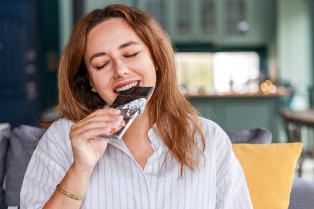 woman eating dark chocolate candy bar