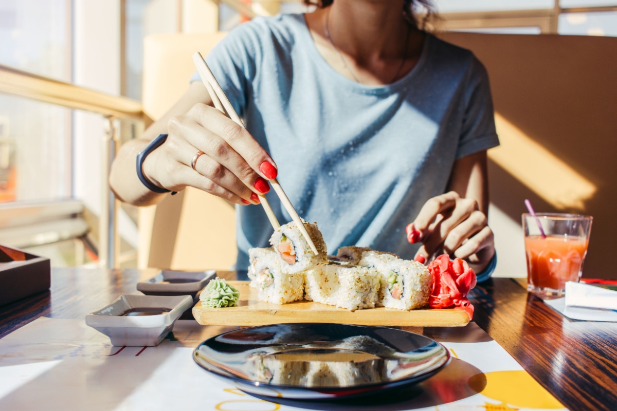 woman eating sushi with chopsticks