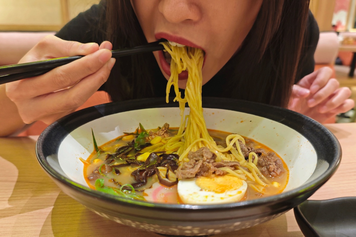 woman enjoying a delicious bowl of ramen with chopsticks