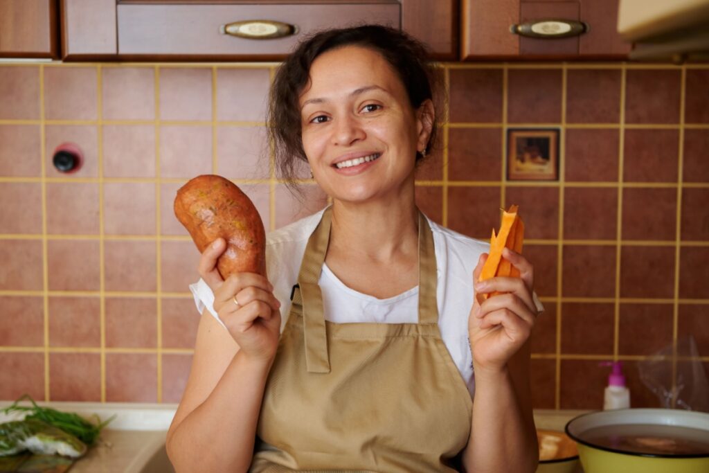 woman holding a sweet potato and batata wedges and smiling