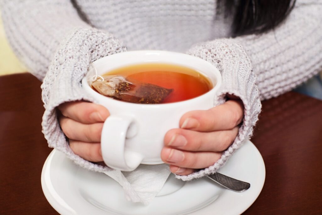 woman holding cup of tea bag