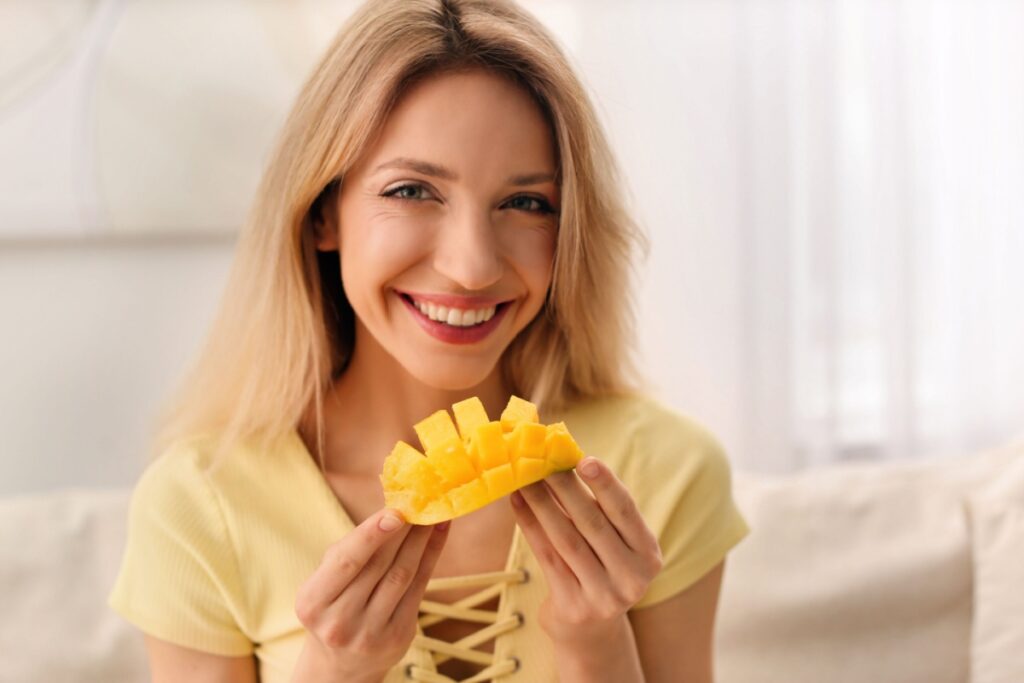 woman holding cut mango fruit