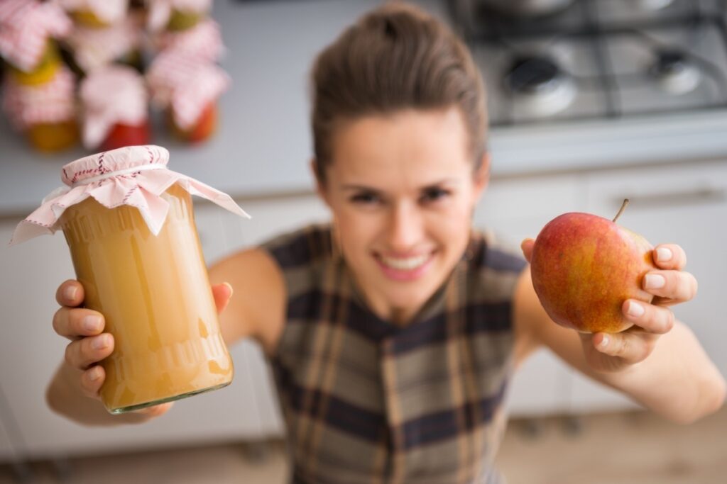 woman holding homemade applesauce and apple