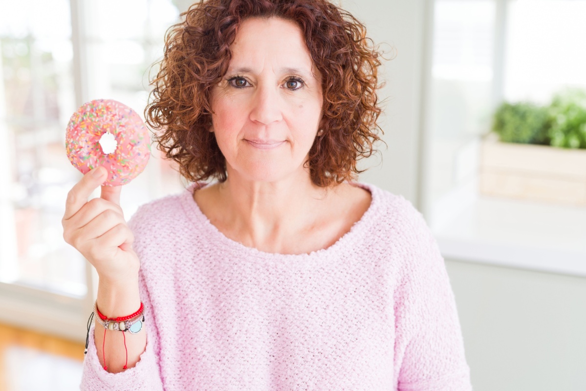 woman in pink holding doughnut dessert