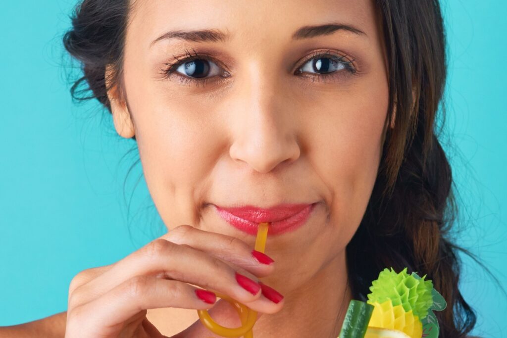 woman sipping on straw fancy drink mocktail