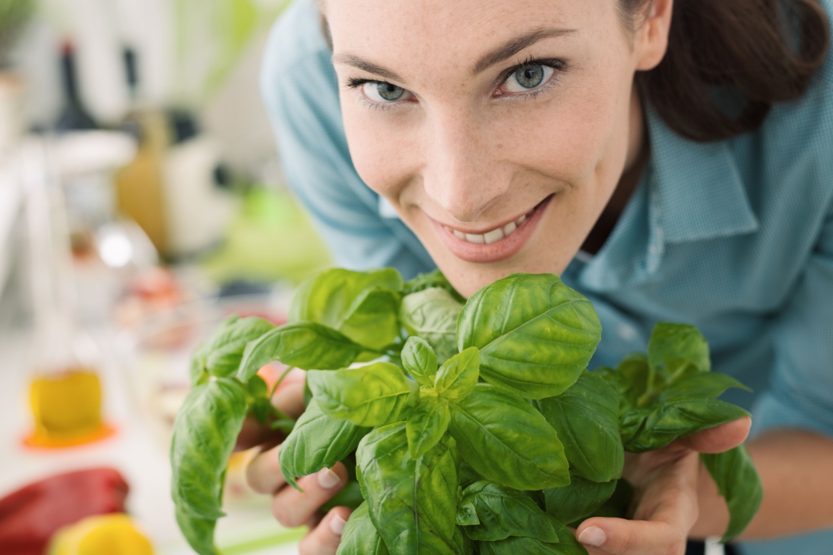 woman smelling fresh basil at home growing herbs