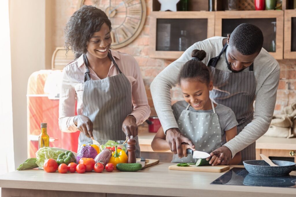 Black family cutting vegetables salad