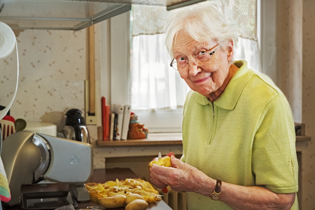 Elderly Woman in the Kitchen Peeling Potatoes