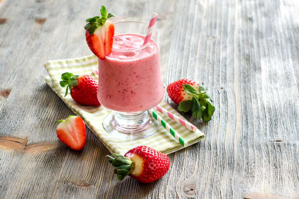 Milk shake with strawberries on wooden copy space background