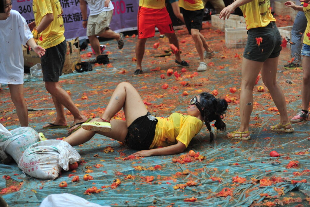 A participant is thrown down by crushed tomatos during the chaos of the Tomatina Festival in Shenyang city, north Chinas Liaoning province, 31 August 2014.
