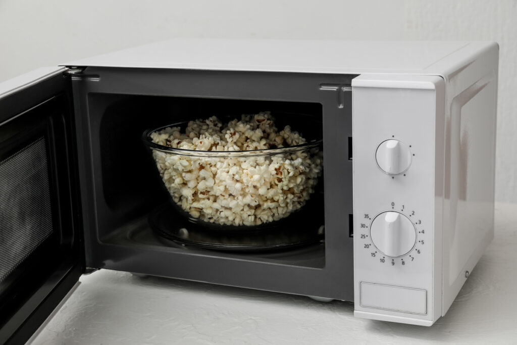 Bowl with popcorn in opened microwave oven