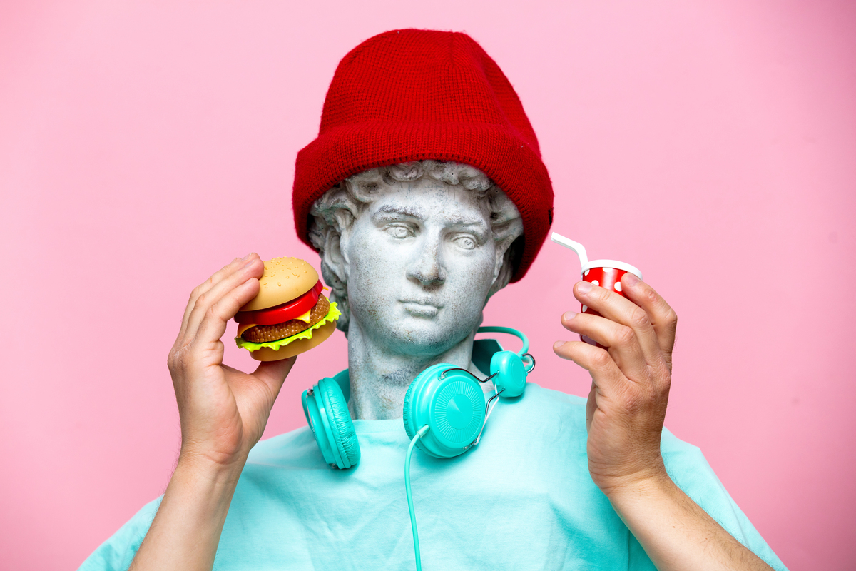 Antique bust of male in hat with cola drink and hamburger on pink background. Ready for summer vacation