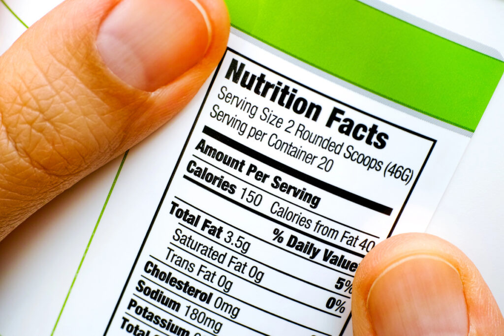 Woman fingers with protein jar. Reading nutrition facts. Closeup.