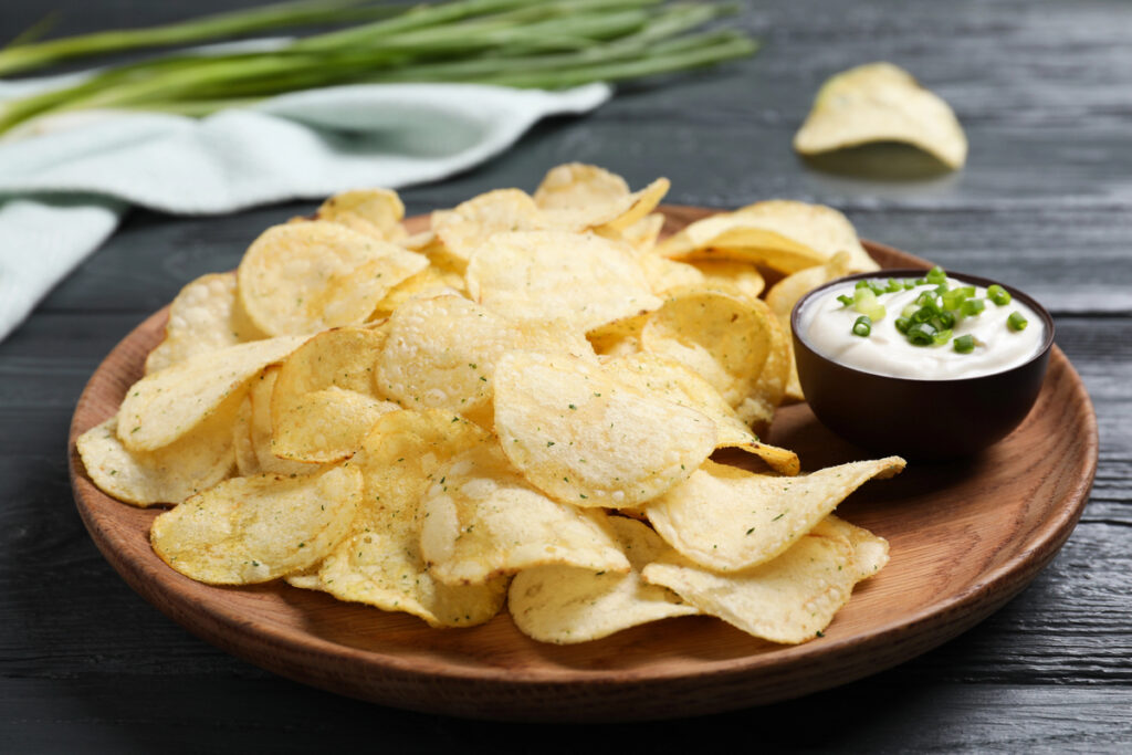 Chips with sour cream dressing on grey wooden table