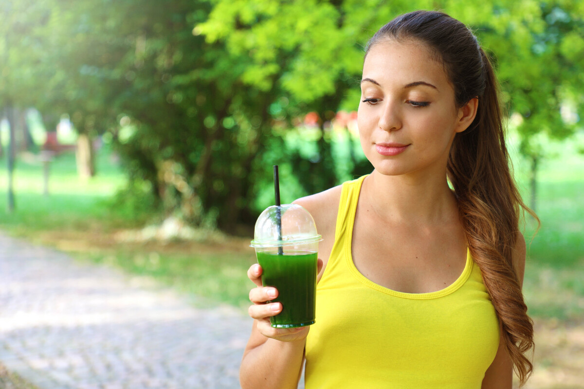 Sporty woman looking at her green detox smoothie