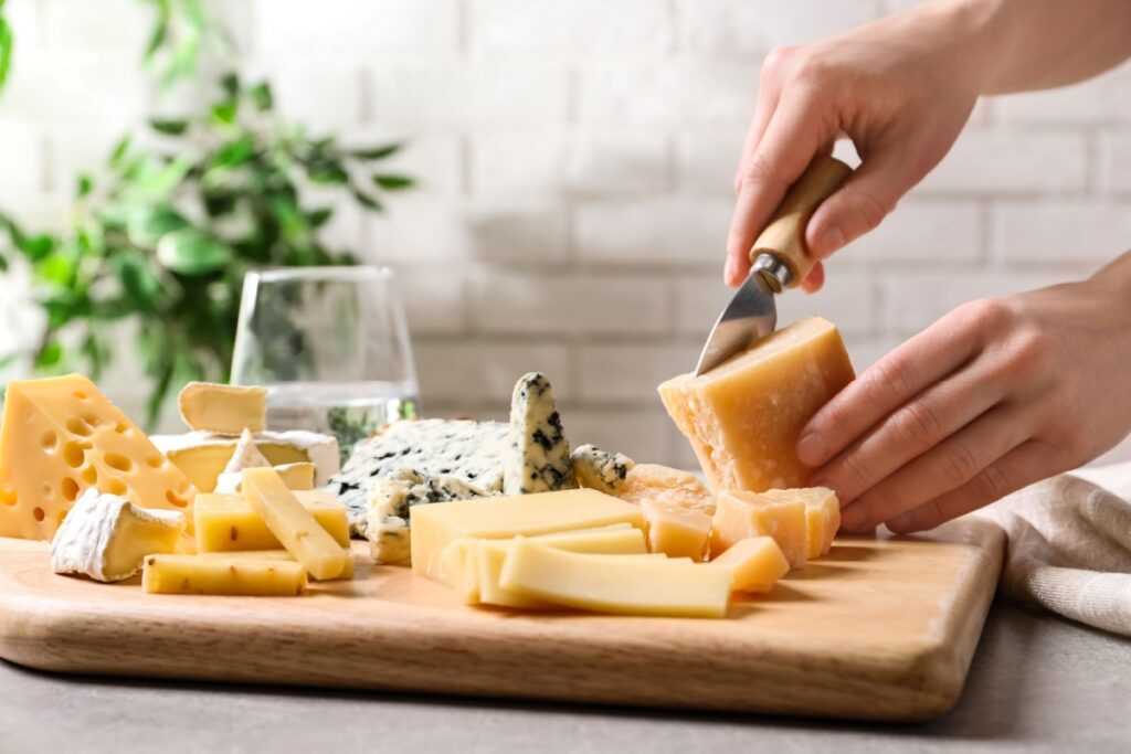 Woman cutting parmesan for cheese plate at table