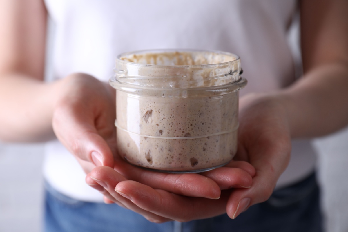 Woman holding glass jar with fresh sourdough starter