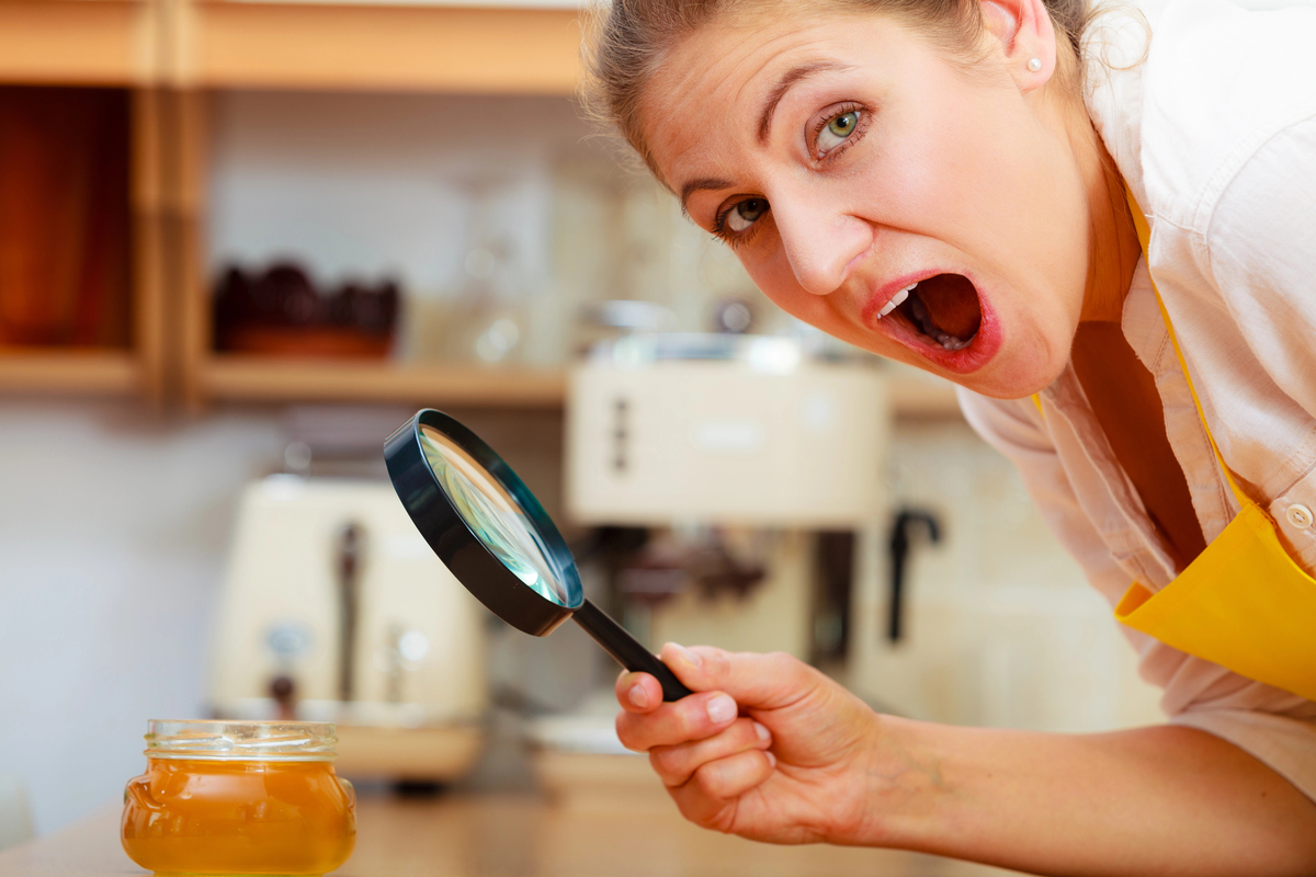 Woman inspecting honey with magnifying glass