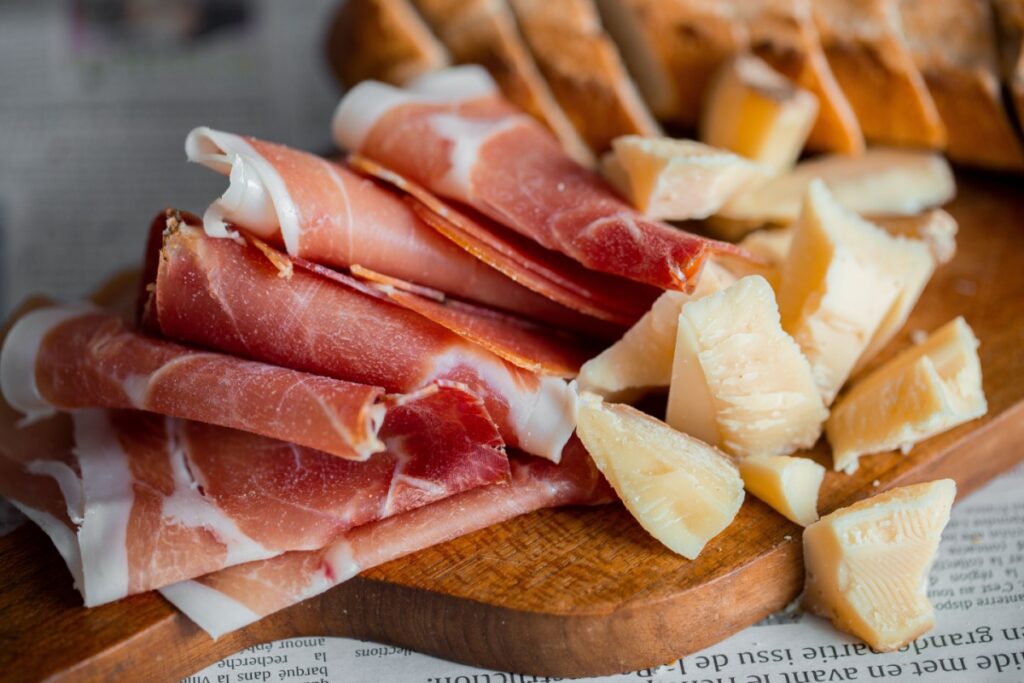 Wooden board with cheese and prosciutto