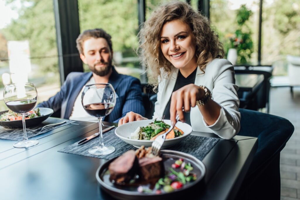 couple drinking wine eating steak on date