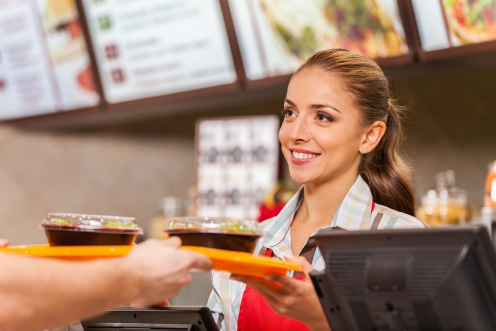 fast food worker handing tray with salads to customer