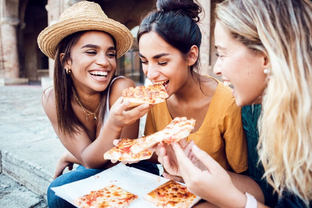 friends eating pizza laughing in Italy