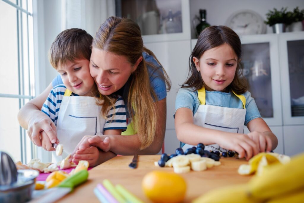 kids with mother preparing a healthy fruit snack in kitchen