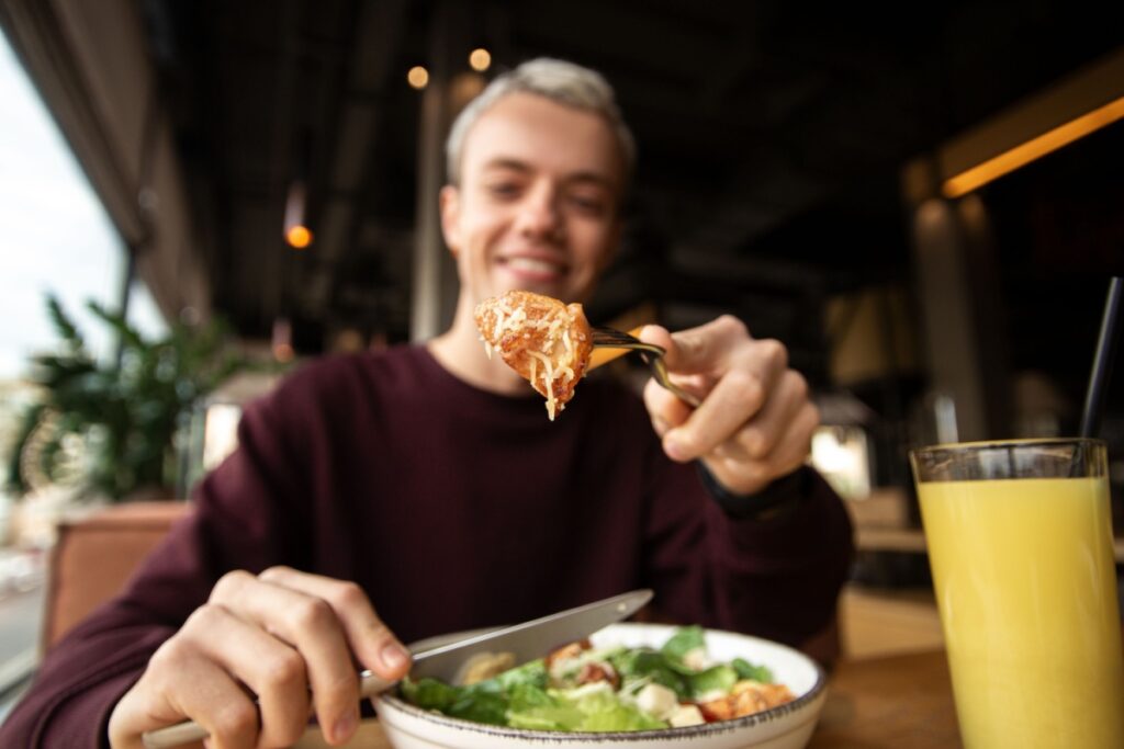 man eating Caesar salad restaurant