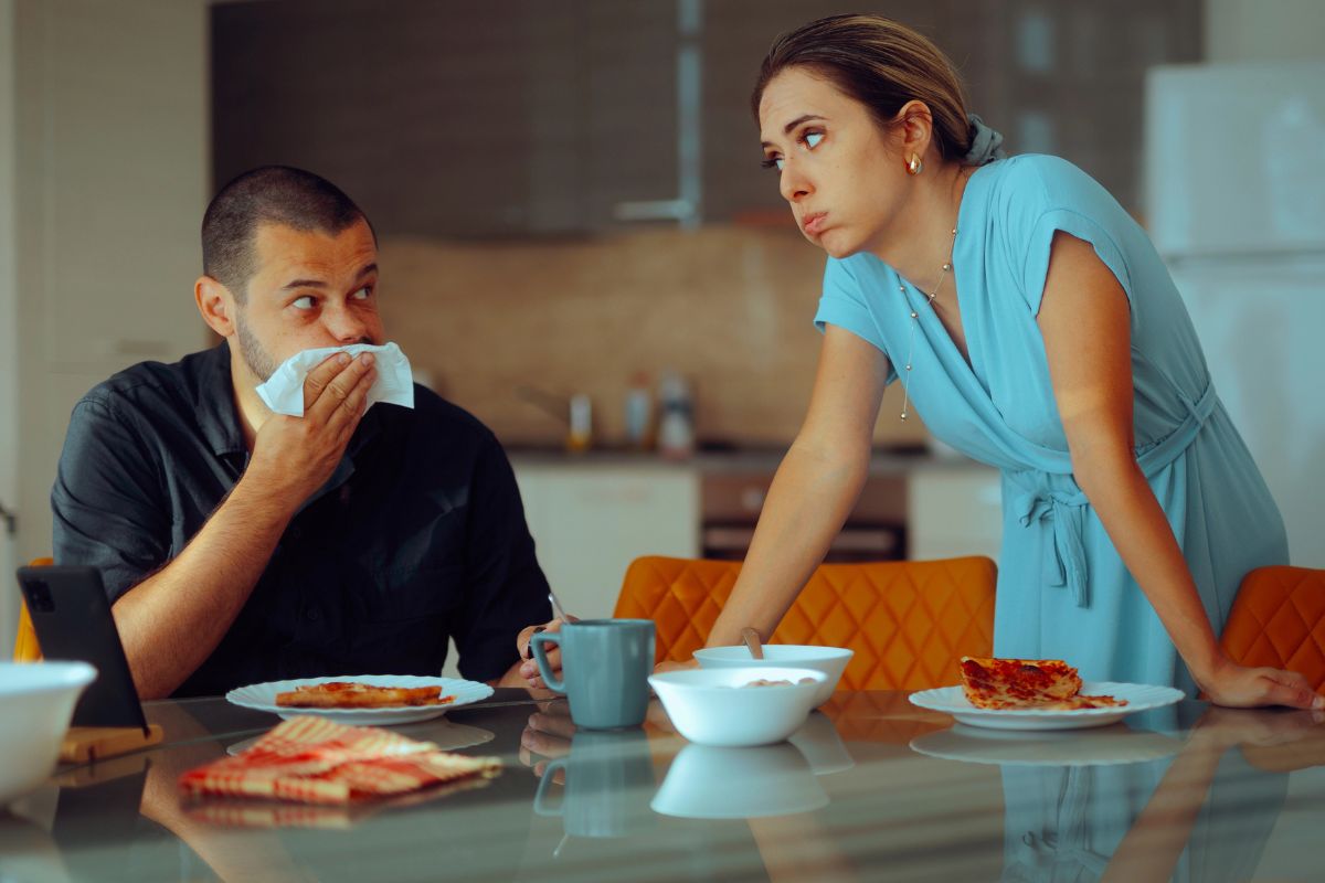 man eating lunch and woman looking at him annoyed