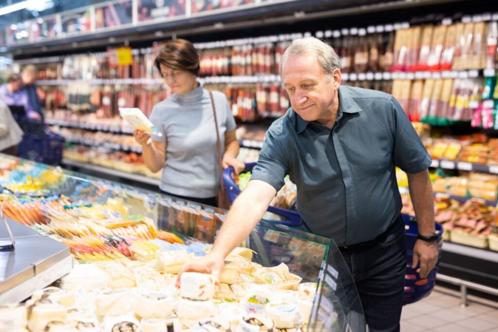 man picking out fresh cheese grocery shopping