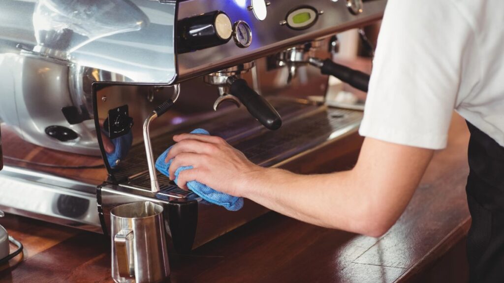 person wiping down coffee machine