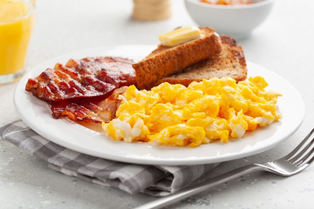 traditional scrambled egg breakfast with bacon and toast