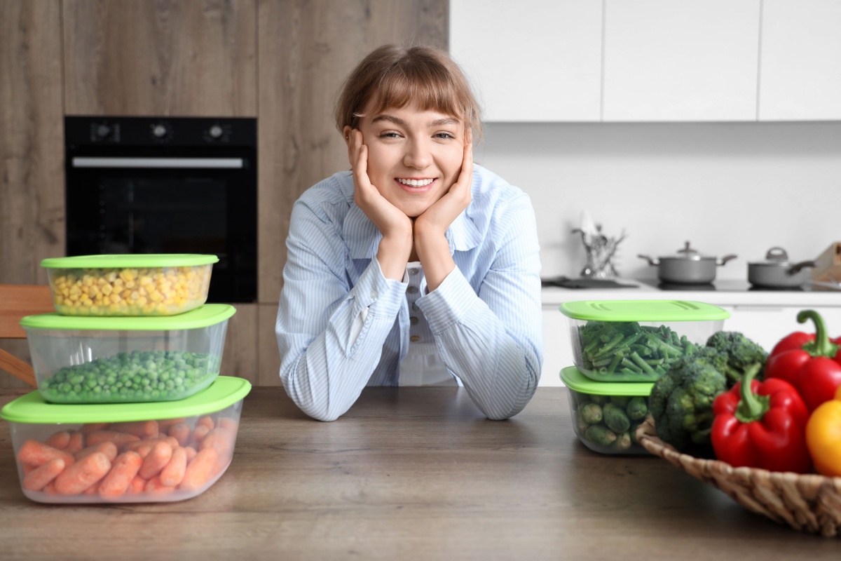 woman and containers with frozen vegetables at table