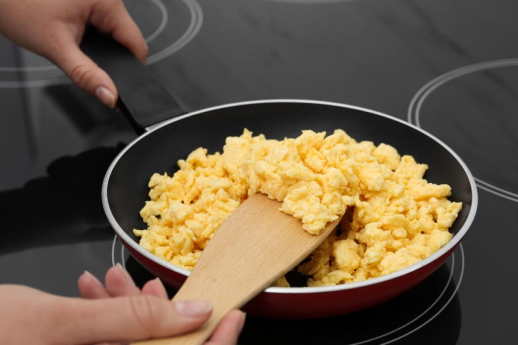 woman cooking scrambled eggs in a pan