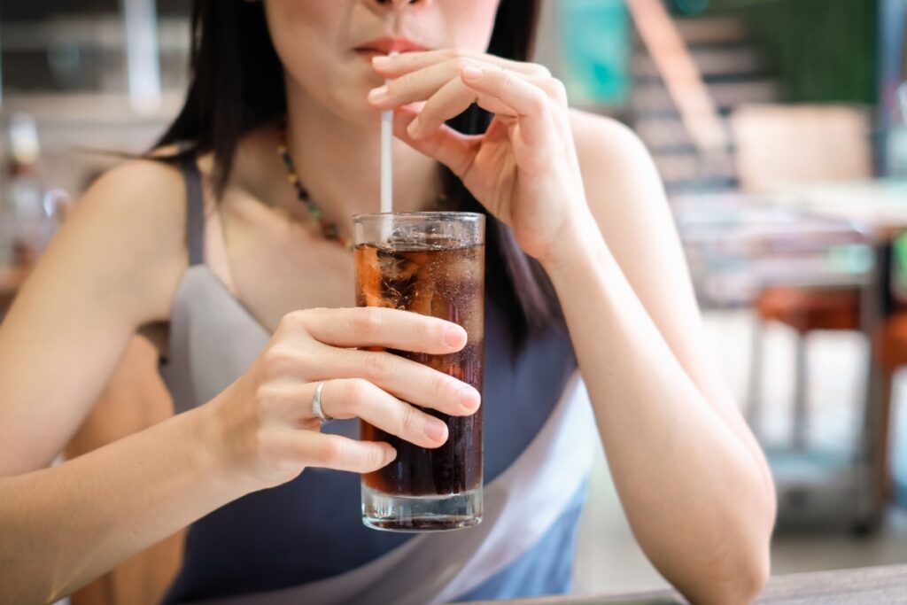 woman drinking soda pop through glass with straw