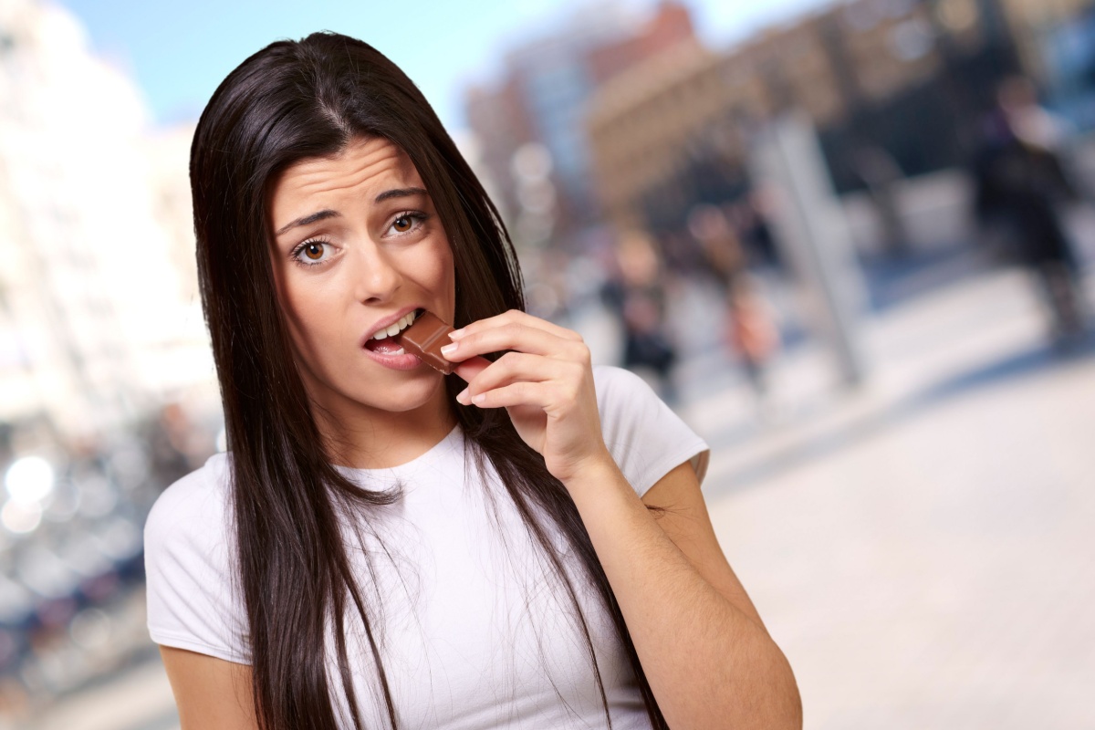 woman eating chocolate bar at city