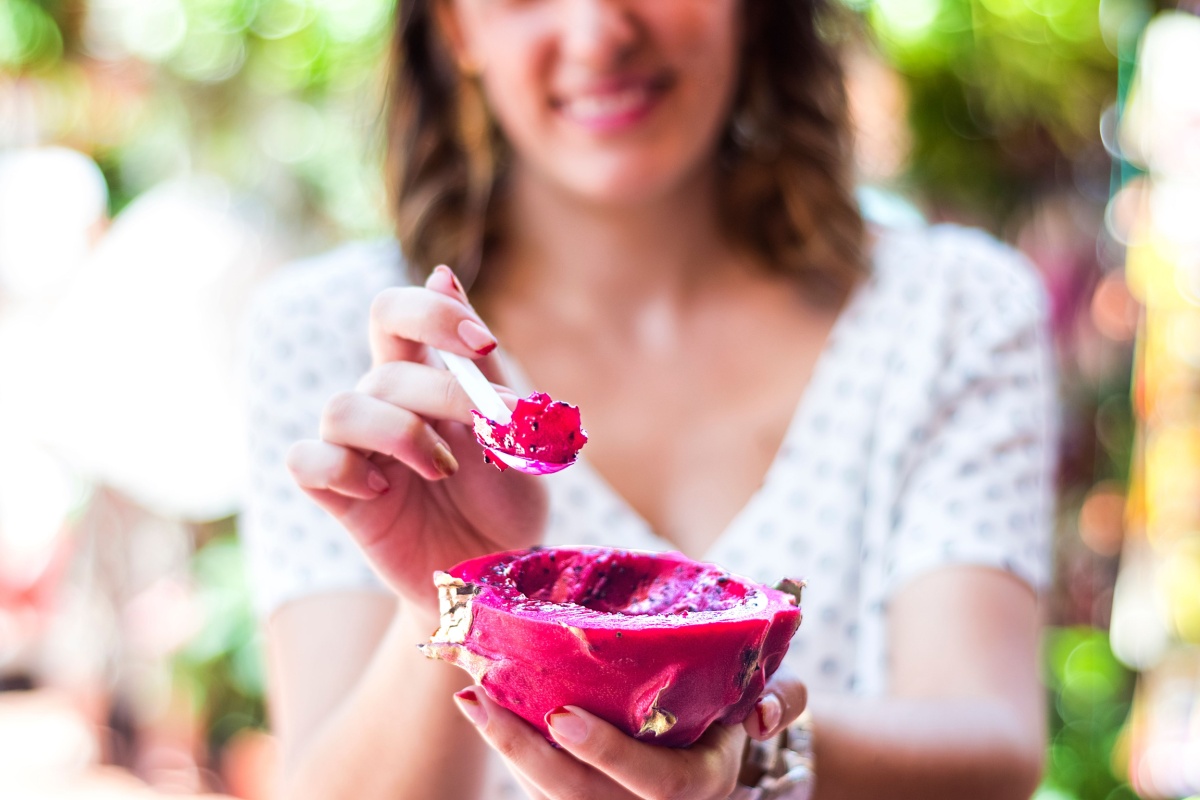 woman eating fresh dragon fruit on spoon