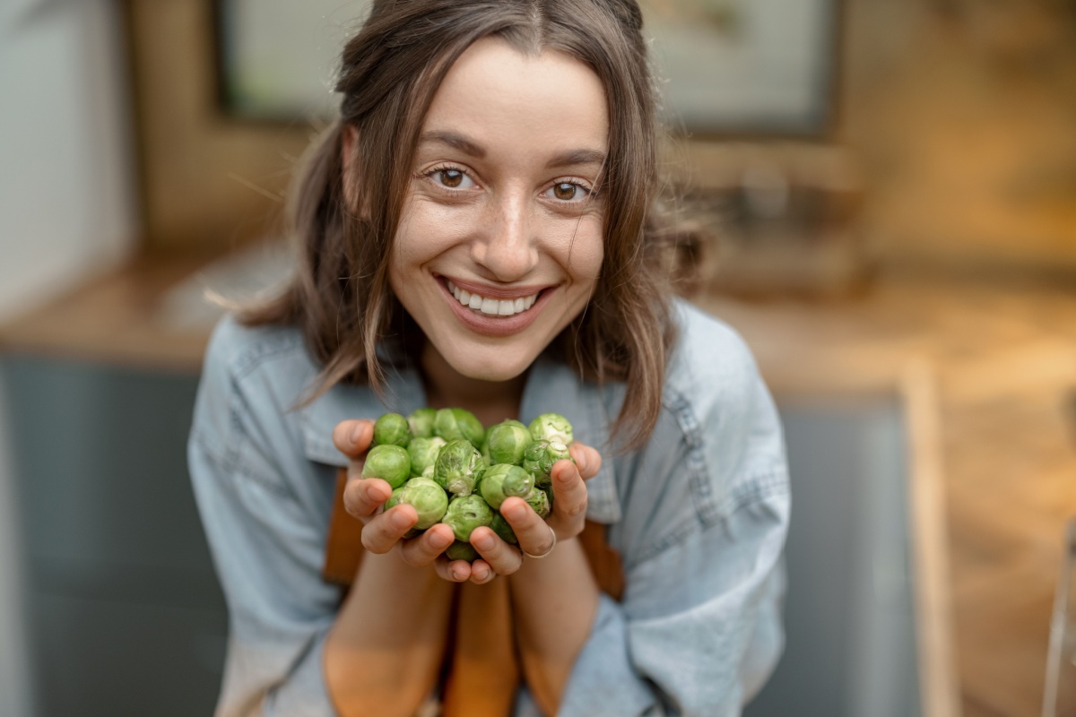 woman holding handful of Brussel sprouts smiling