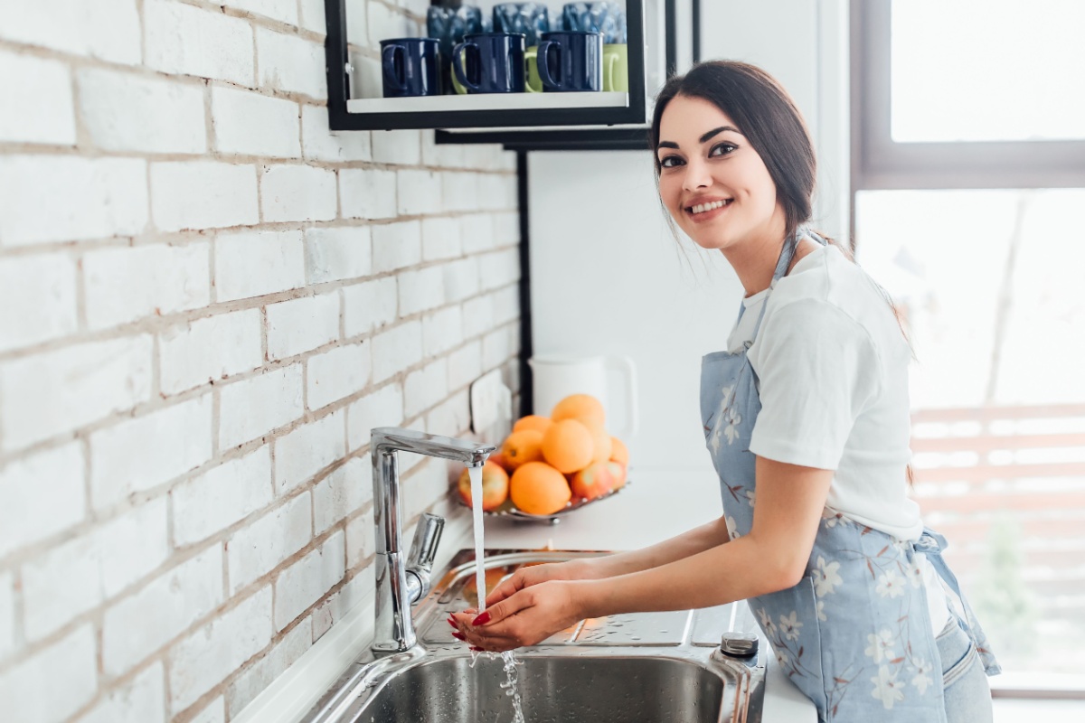 woman in apron washing hands kitchen sink