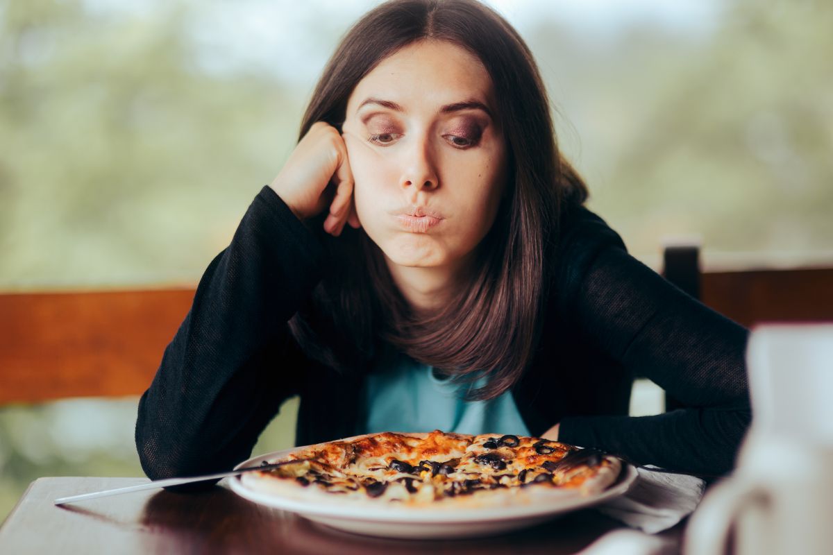 woman looking bored at her pizza