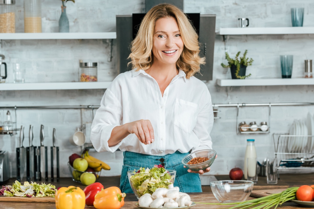 woman sprinkling nuts on salad