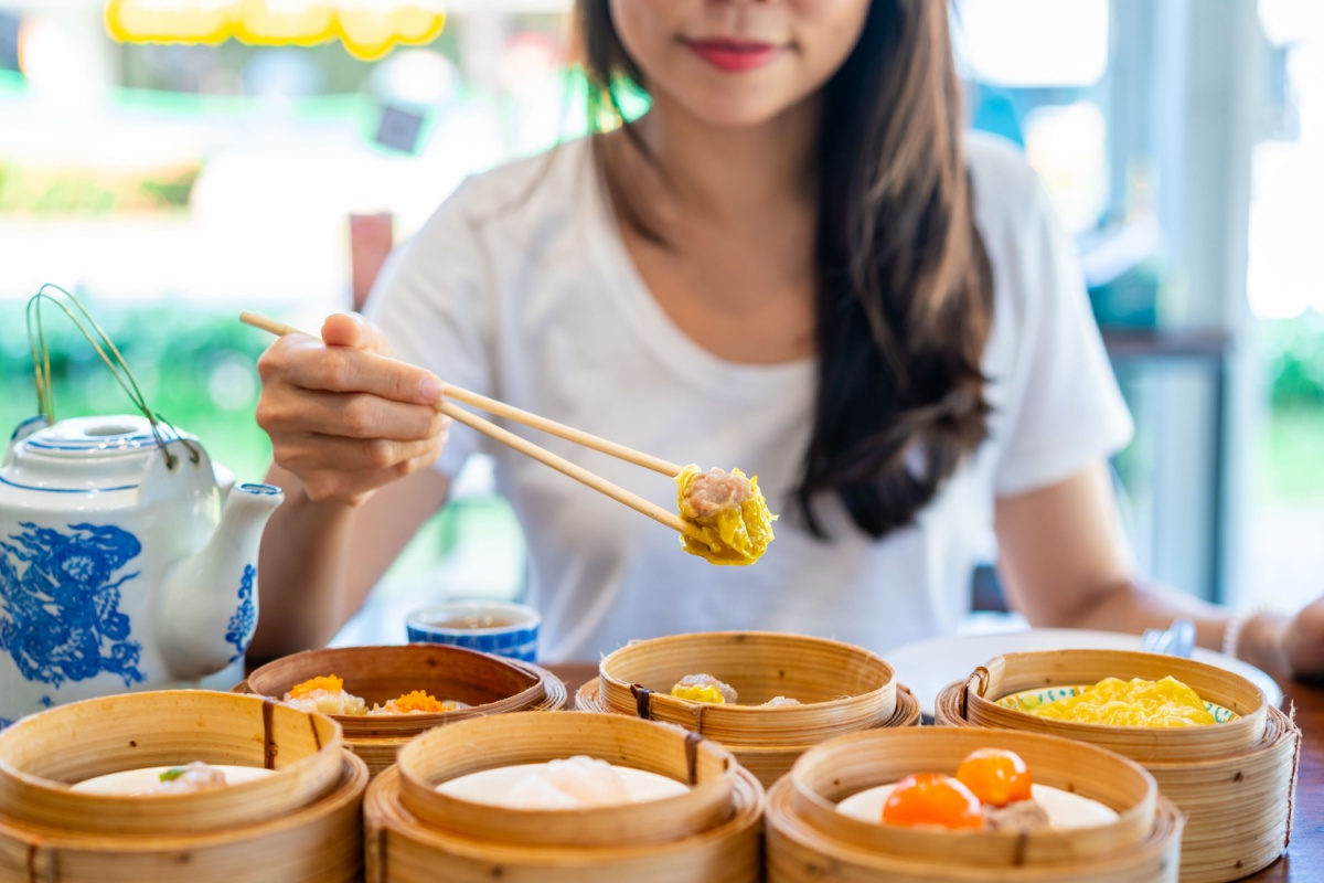 woman traveler eating traditional Chinese Dim Sum at restaurant