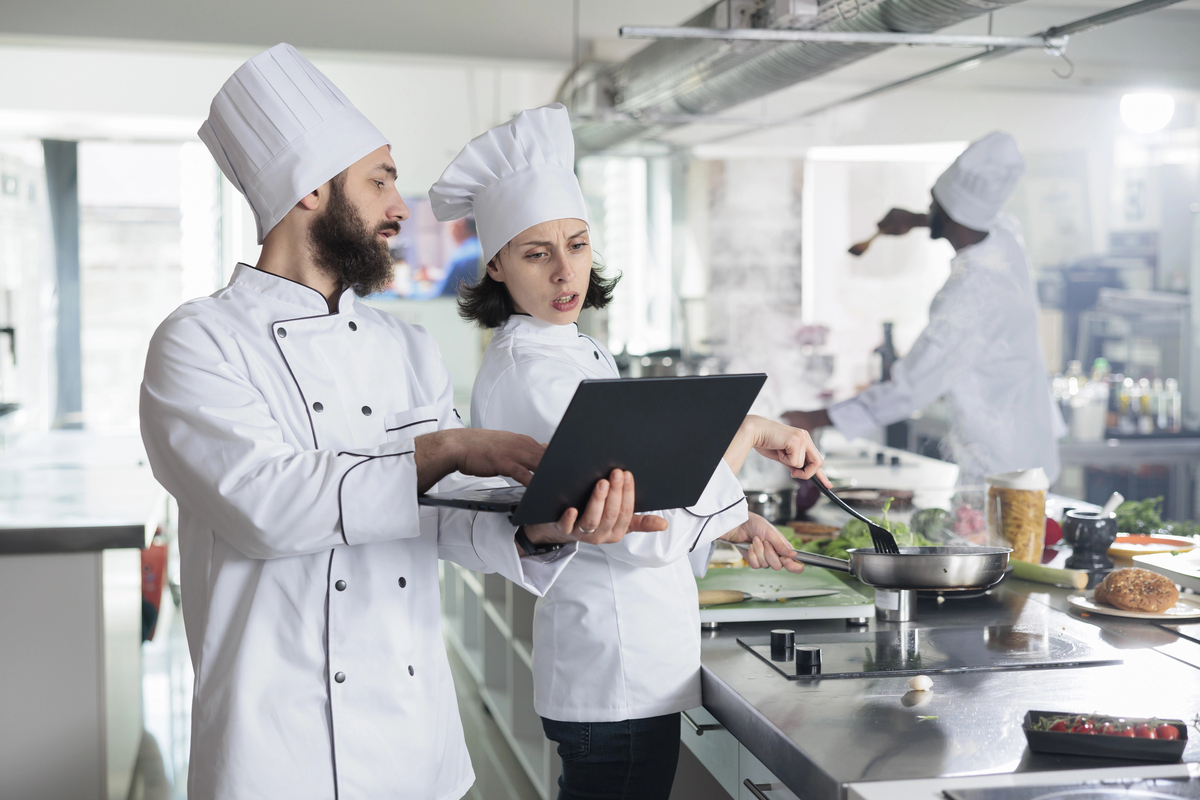 Head chef with modern laptop showing gourmet dish recipe