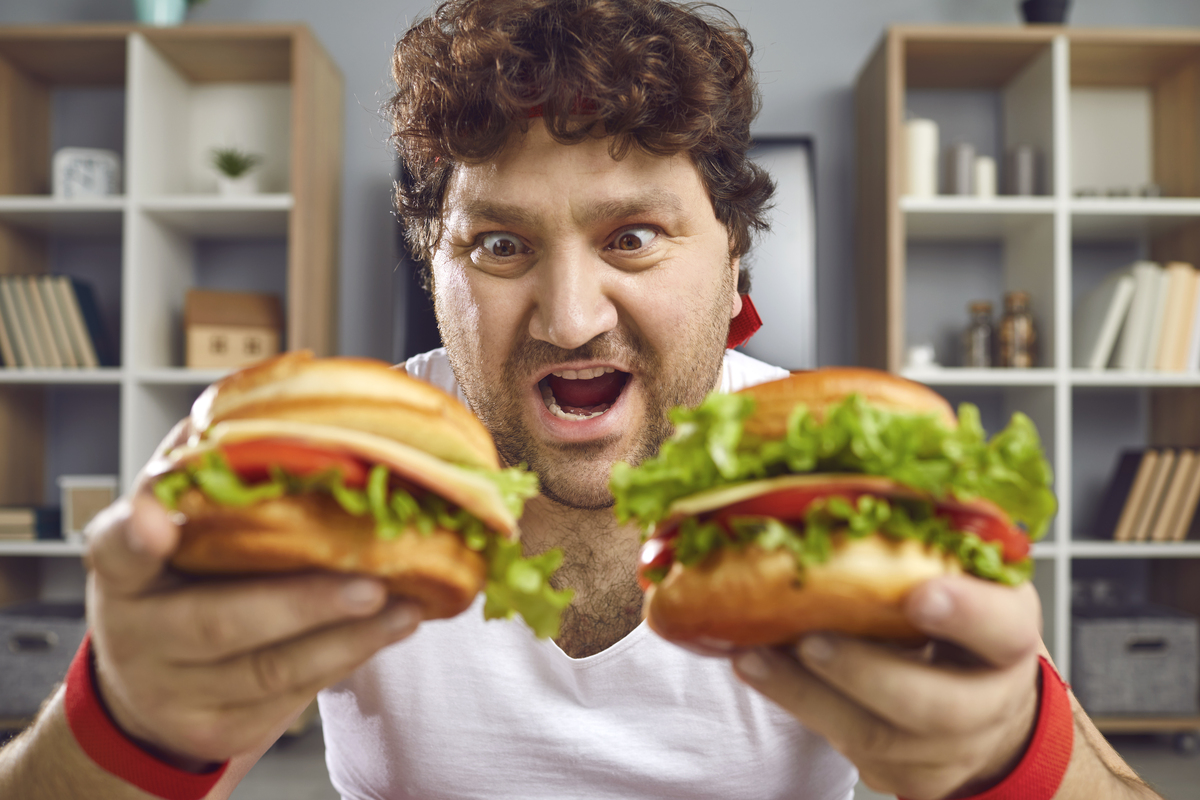 Hungry chubby man looking at two delicious hamburgers