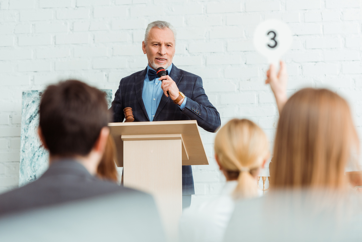 Selective focus of auctioneer talking with microphone and looking at buy