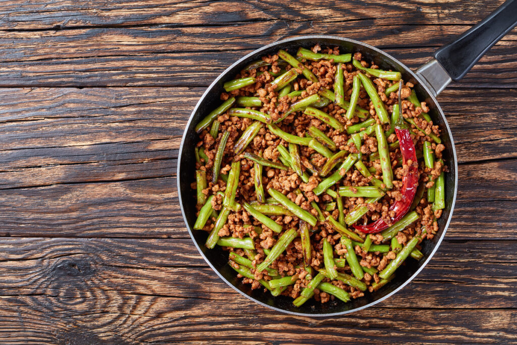 Szechuan Stir Fried Green Beans with ground pork in a skillet, view from above, close up