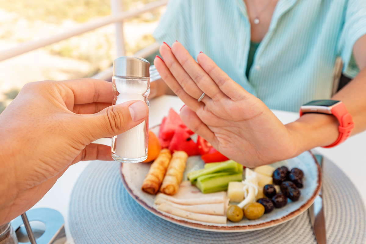 Woman in a restaurant refuses the offered salt and pepper shaker with a gesture of her hand. Diet for gout and high cardiovascular blood pressure