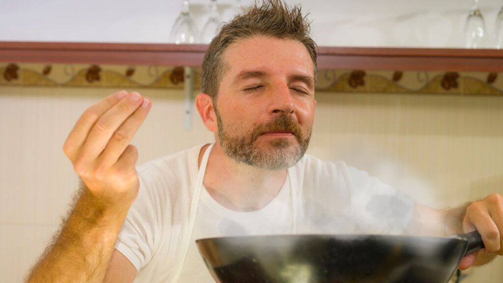 man smelling food in kitchen